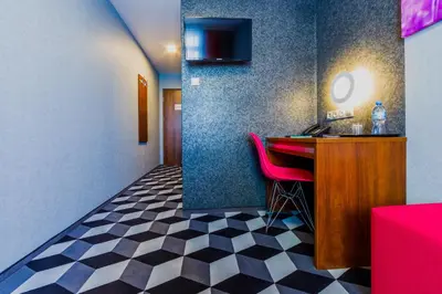 a hotel room with a bar with a pink chair at Hotel Wyspiański in Kraków