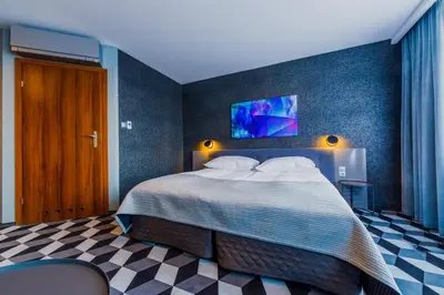 a bedroom with a large bed with a blue wall at Hotel Wyspiański in Kraków