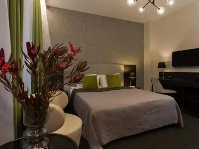 a bedroom with a bed and a table with a vase of flowers at Hotel Atrium in Kraków
