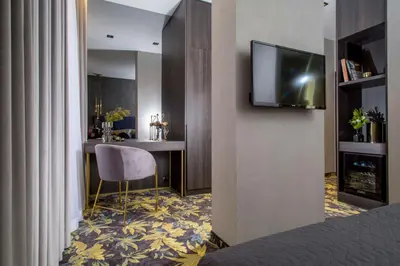 a hotel room with a bed and a television on a wall at Hotel Atrium in Kraków