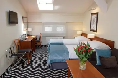 a hotel room with two beds and a table with flowers at Hotel Senacki in Kraków
