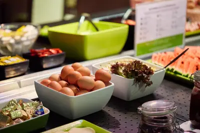 a counter with bowls of eggs and other food at CAMPANILE PRIME Krakow Old Town in Kraków