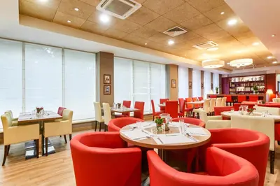 a restaurant with red chairs and tables in a room at CAMPANILE PRIME Krakow Old Town in Kraków
