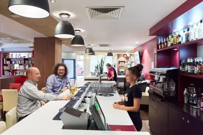 a group of people standing at a counter in a bar at CAMPANILE PRIME Krakow Old Town in Kraków