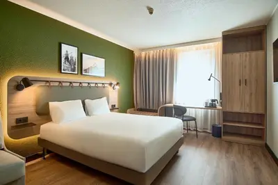 a bedroom with a white bed and a green wall at CAMPANILE PRIME Krakow Old Town in Kraków