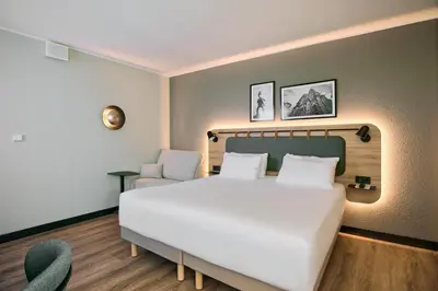a bedroom with a large white bed and a chair at CAMPANILE PRIME Krakow Old Town in Kraków