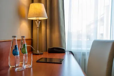 a table with two bottles and a lamp and a phone at Hotel Krakus in Kraków