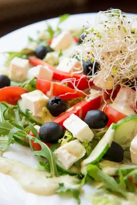 a salad with cheese and olives on a white plate at Hotel Krakus in Kraków