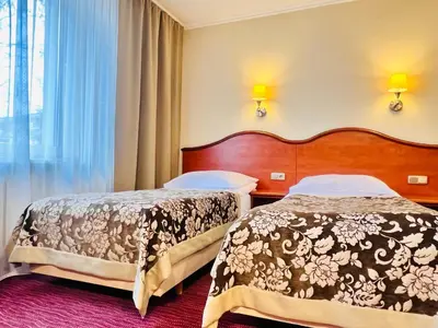a hotel room with two beds and a window at Hotel Krakus in Kraków