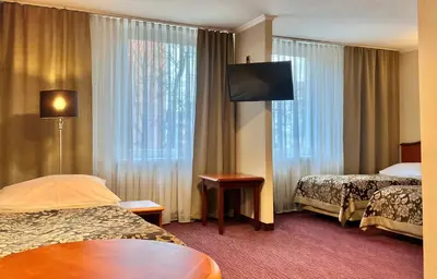 a hotel room with two beds and a flat screen tv at Hotel Krakus in Kraków