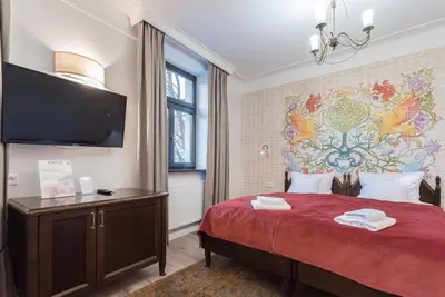 a bedroom with a large red bed with a tv on the wall at Hotel Ester in Kraków