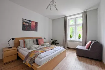 a bedroom with a bed and a chair and a window at Urban Nest Apartments Wietora 8 in Kraków