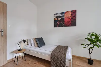 a white couch in a white room with a plant at Urban Nest Apartments Wietora 8 in Kraków