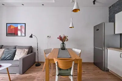 a kitchen and living room with a table and a couch at Urban Nest Apartments Wietora 8 in Kraków