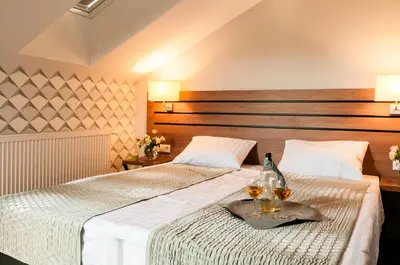 two beds in a hotel room with two glasses of wine at Hotel Wilga in Kraków