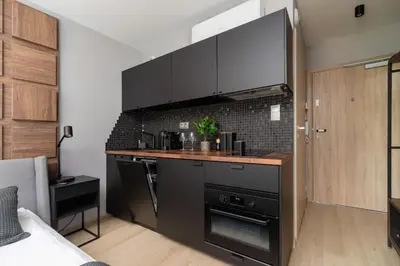 a kitchen with black cabinets and a counter top at Modern Apartment Śródmiescie Kraków by Noclegi Renters in Kraków