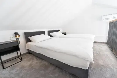 a bedroom with a bed with white sheets and a table at Domki na Łące in Libiąż