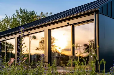 a glass house with the sun setting through the windows at Domki na Łące in Libiąż