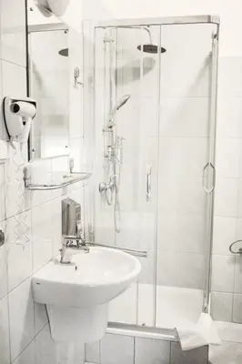 a white bathroom with a sink and a shower at Hotel Eden in Kraków