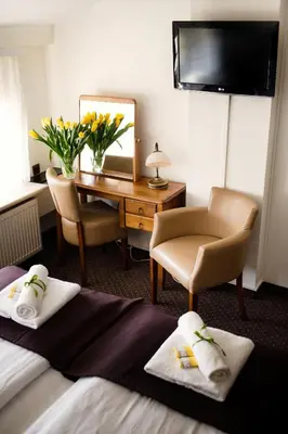 a hotel room with two beds and a desk at Hotel Eden in Kraków