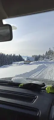 a dog laying on the dashboard of a car in the snow at Gościniec Dziubasowki in Nowy Targ