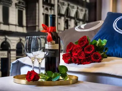 a bottle of wine and a glass on a table with roses at Hotel Logos Kraków in Kraków