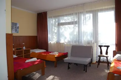 a room with two beds and a chair and a window at Hotel Bona in Kraków