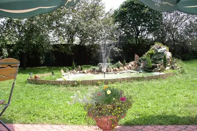 a garden with a fountain and flowers in the grass at Hotel Bona in Kraków