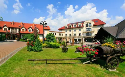 a garden with a horse drawn cart in front of a building at Hotel Galicja Wellness & SPA in Oświęcim