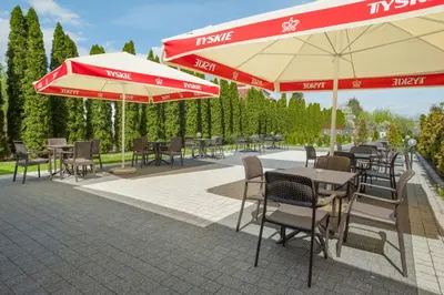 a patio with tables and chairs and umbrellas at Express Kraków Hotel in Kraków
