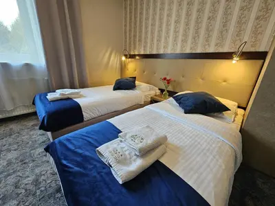a hotel room with two beds and a table and chairs at Hotel Galicja SPA Wieliczka in Wieliczka