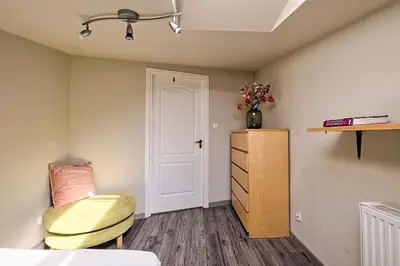 a bedroom with a yellow chair and a cabinet at Urban Nest Apartments Radziwiłłowska 14 in Kraków