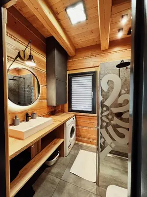 a bathroom with a sink and a washing machine at Domek z bali drewnianych w górach Jacuzzi & Balia - Osada Chełm in Stróża