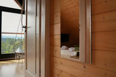 a bedroom with a mirror in a wooden wall at Domek z bali drewnianych w górach Jacuzzi & Balia - Osada Chełm in Stróża