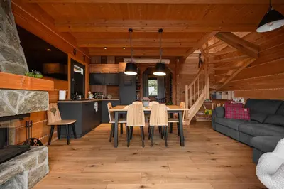 a dining room and living room with a table and chairs at Domek z bali drewnianych w górach Jacuzzi & Balia - Osada Chełm in Stróża