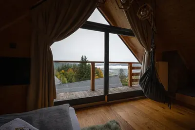 a living room with a large window in a house at Domek z bali drewnianych w górach Jacuzzi & Balia - Osada Chełm in Stróża