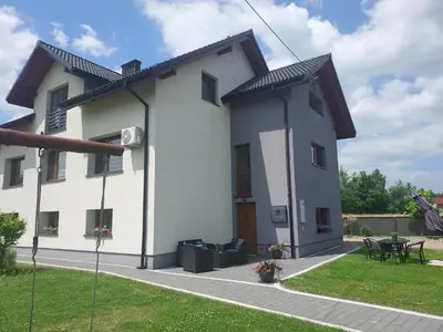 a white house with a table and a patio at Apartamenty Happy House in Zator