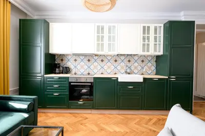 a green kitchen with white cabinets and a couch at Native Apartments Nowowiejska 9 Deluxe in Kraków