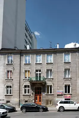 a large brick building with cars parked in front of it at Native Apartments Nowowiejska 9 Deluxe in Kraków