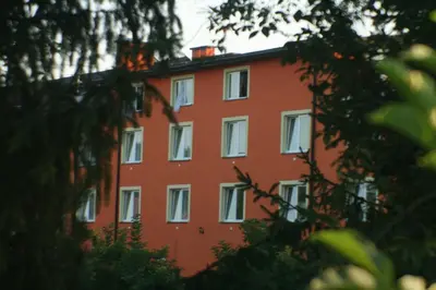 a red building with white windows and trees at Hotel Daisy Budget in Kraków