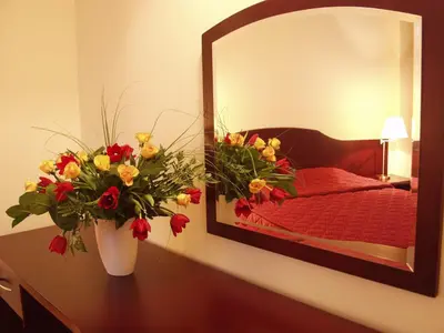 a vase of flowers on a table in front of a mirror at Matejko Hotel in Kraków