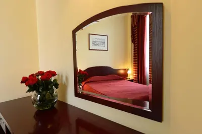 a mirror on a wall with a bed in a room at Matejko Hotel in Kraków