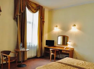 a hotel room with a desk and a bed and a mirror at Matejko Hotel in Kraków