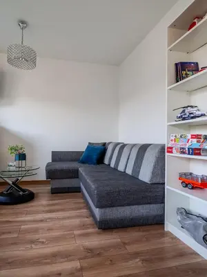 a living room with a gray couch and wooden floors at Wspomnienie młodości in Kraków