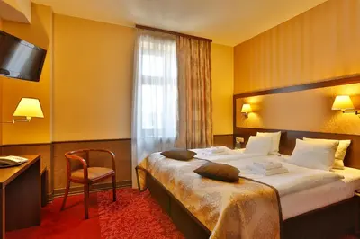 a hotel room with a bedroom with a desk and a television at Hotel Wielopole in Kraków
