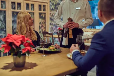 a man holding a bottle of wine at a table at Zajazd Srebrna Gora in Kraków