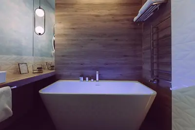 a bathroom with a white tub and a wooden wall at Zajazd Srebrna Gora in Kraków