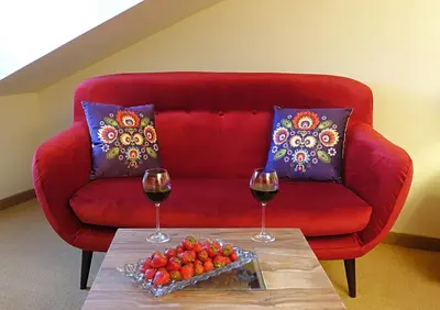a red couch with two glasses of wine on a table at Zajazd Srebrna Gora in Kraków