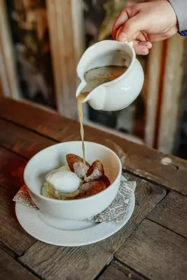a person is pouring coffee into a bowl of food at Zajazd Srebrna Gora in Kraków
