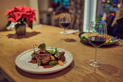 a table with a plate of food and a glass of wine at Zajazd Srebrna Gora in Kraków